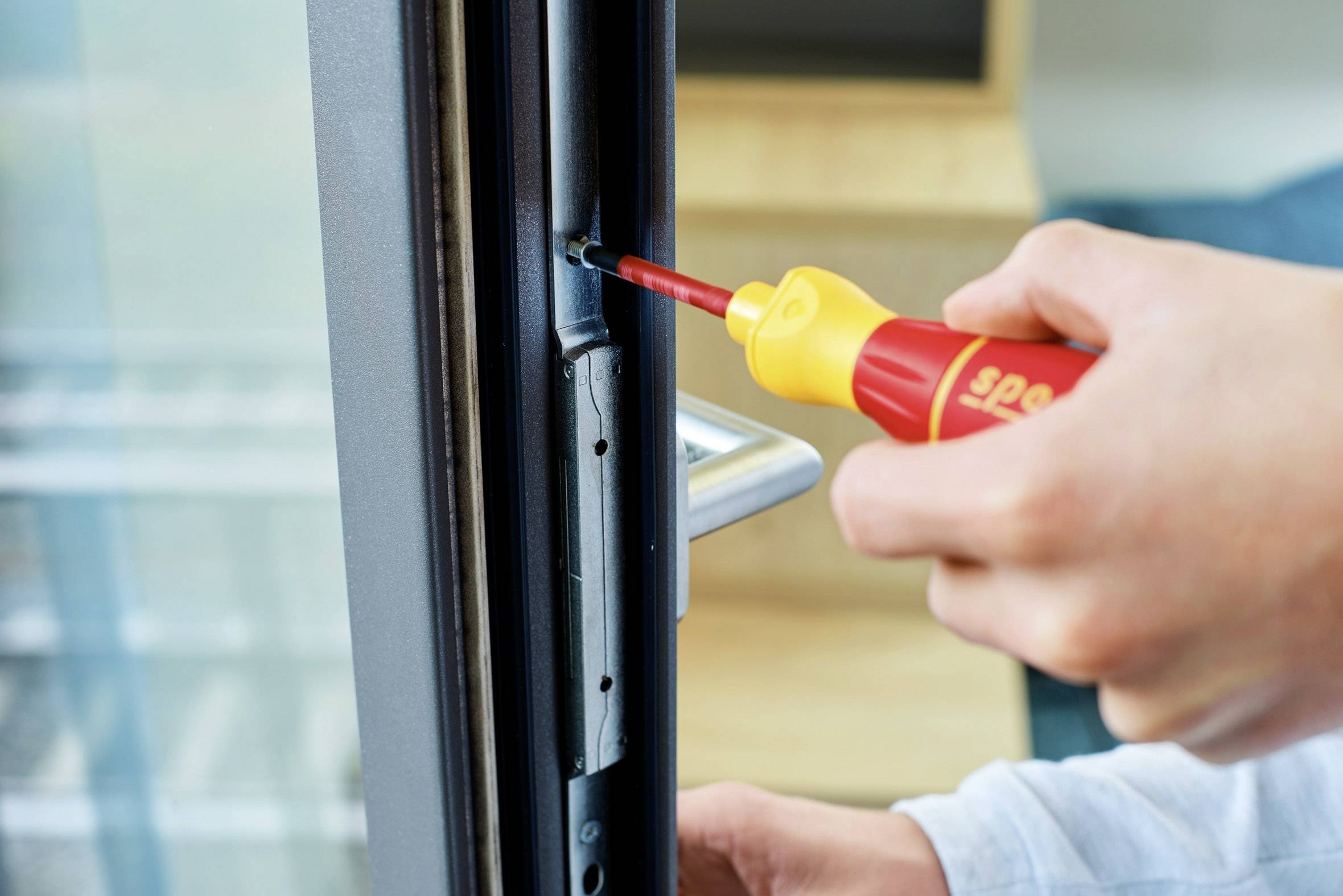 Una persona sta stringendo una vite sul bordo di una finestra con un cacciavite per riparare o sistemare la finestra.