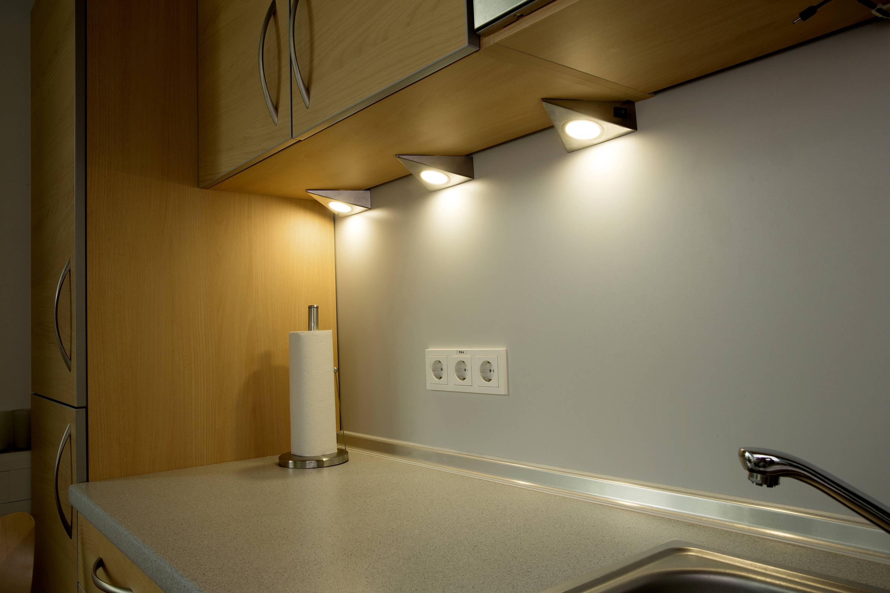 Cucina con area di lavoro illuminata; le finestre superiori illuminano il piano di lavoro grigio e le prese elettriche, il portarotolo di carta è a sinistra.