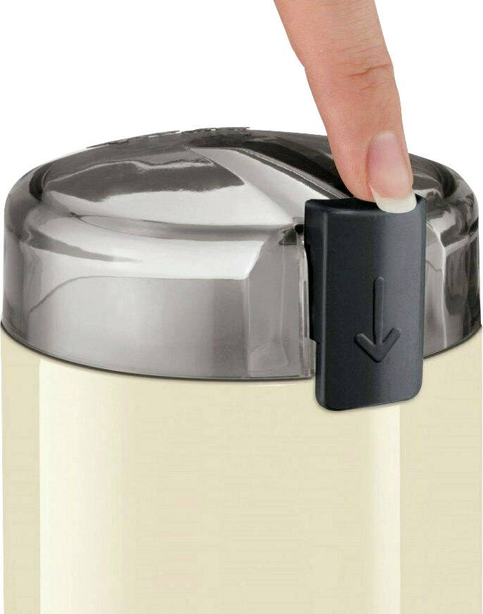 Una mano preme sul meccanismo di apertura di un bicchiere con coperchio. Il coperchio ha un segno a freccia che indica la direzione della pressione.