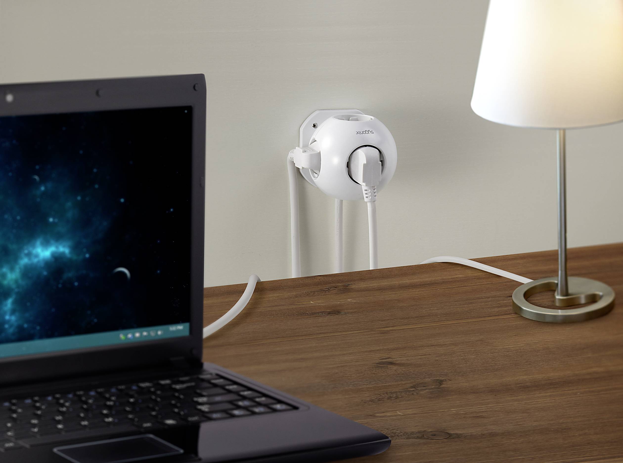 Tavolo per laptop con lampada e presa a muro, nella quale è inserito un caricabatterie. Lo schermo del laptop mostra un motivo spaziale.