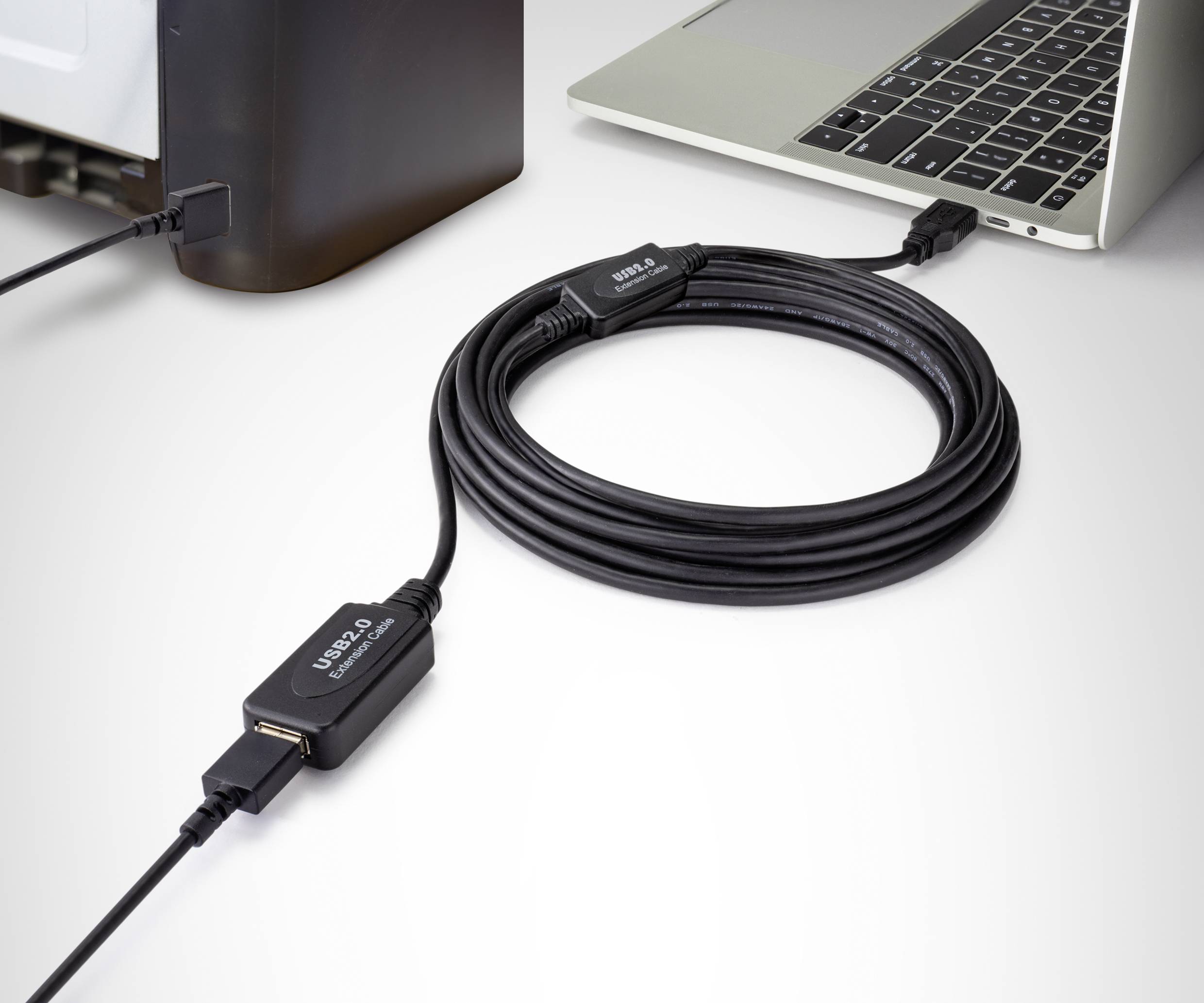 Un cavo di prolunga USB 2.0 collega un computer desktop a un laptop. Il cavo è arrotolato e ben visibile.