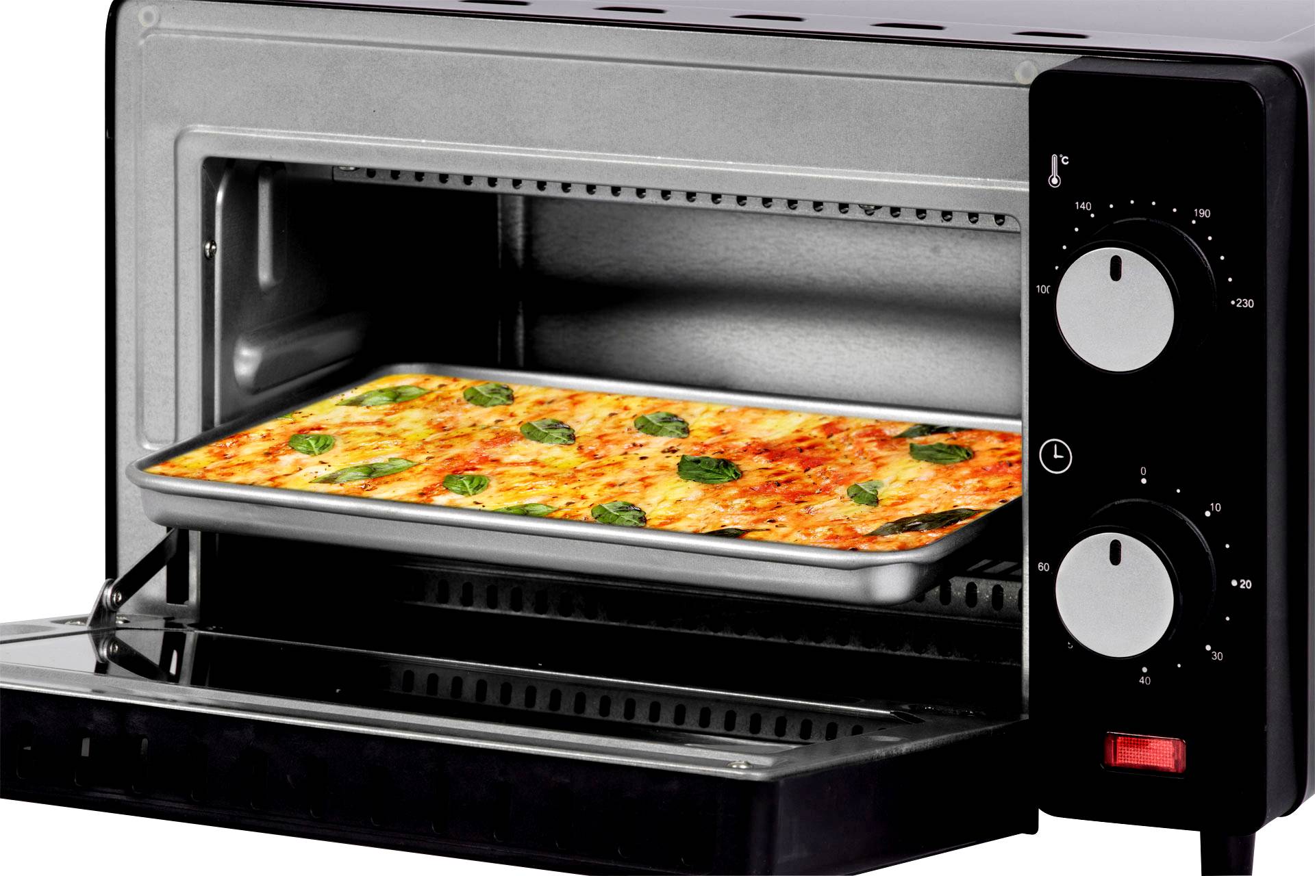 Un forno con lo sportello aperto mostra una pizza rettangolare con formaggio e basilico su una teglia all'interno.