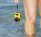 Una fotocamera gialla impermeabile è tenuta in mano da una persona che sta fino alle ginocchia nell'acqua trasparente.