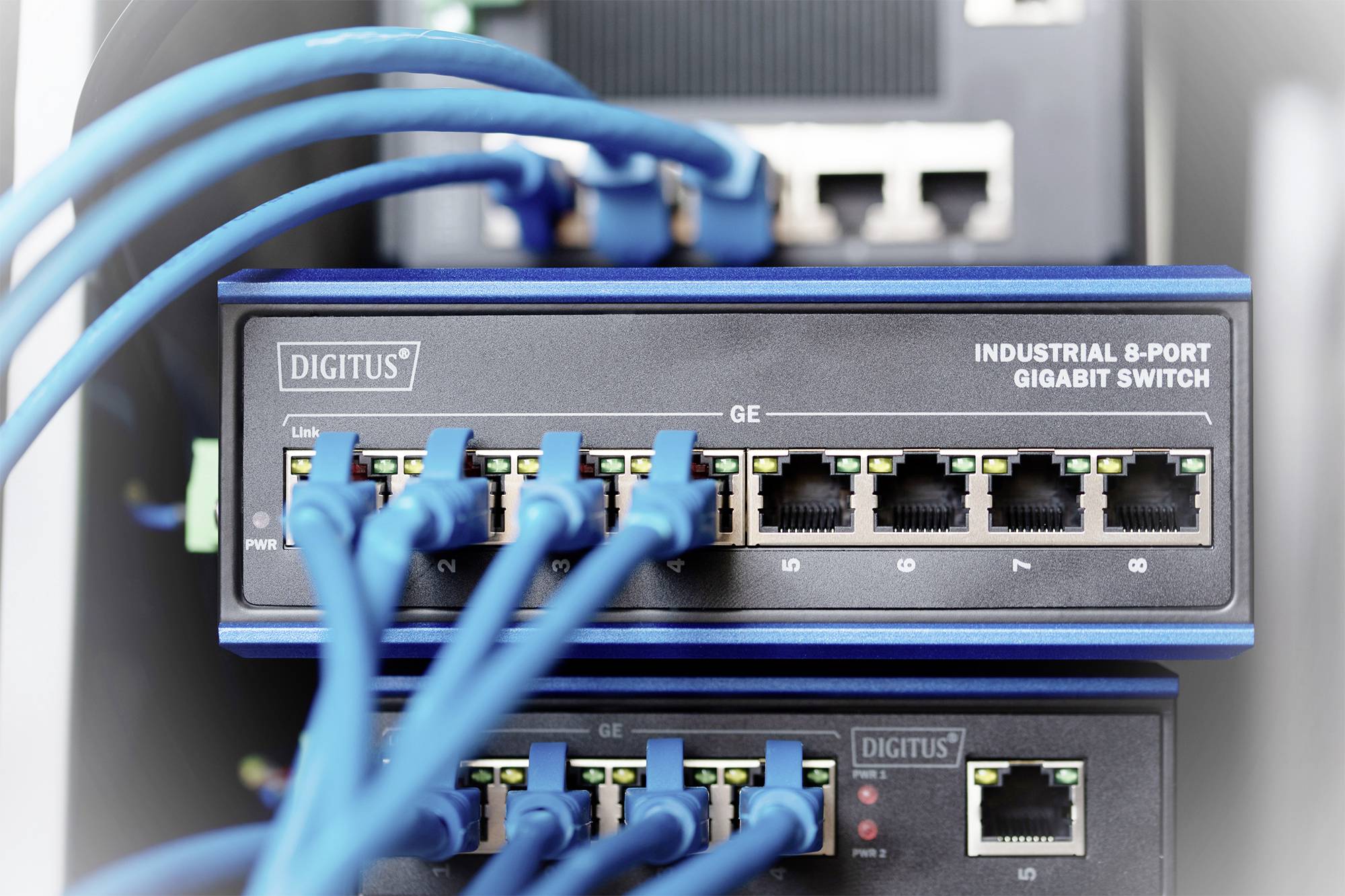 Un 'Industrial 8-Port Gigabit Switch' con diversi cavi Ethernet blu collegati, sistemato in un rack per server.