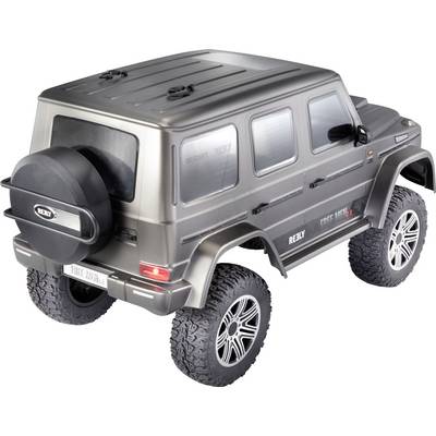 Un'auto radiocomandata in stile fuoristrada con pneumatici grandi e una ruota di scorta. Ha la forma di un SUV con un involucro scuro.