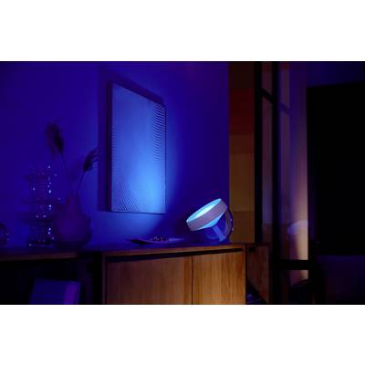 Un soggiorno con illuminazione soffusa, una luce blu risalta un'opera d'arte sulla parete. L'ambiente appare moderno e suggestivo.