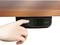 Una mano preme su un controllo digitale sotto un tavolo di legno, che mostra la regolazione dell'altezza e un display con l'indicazione '84.6'.