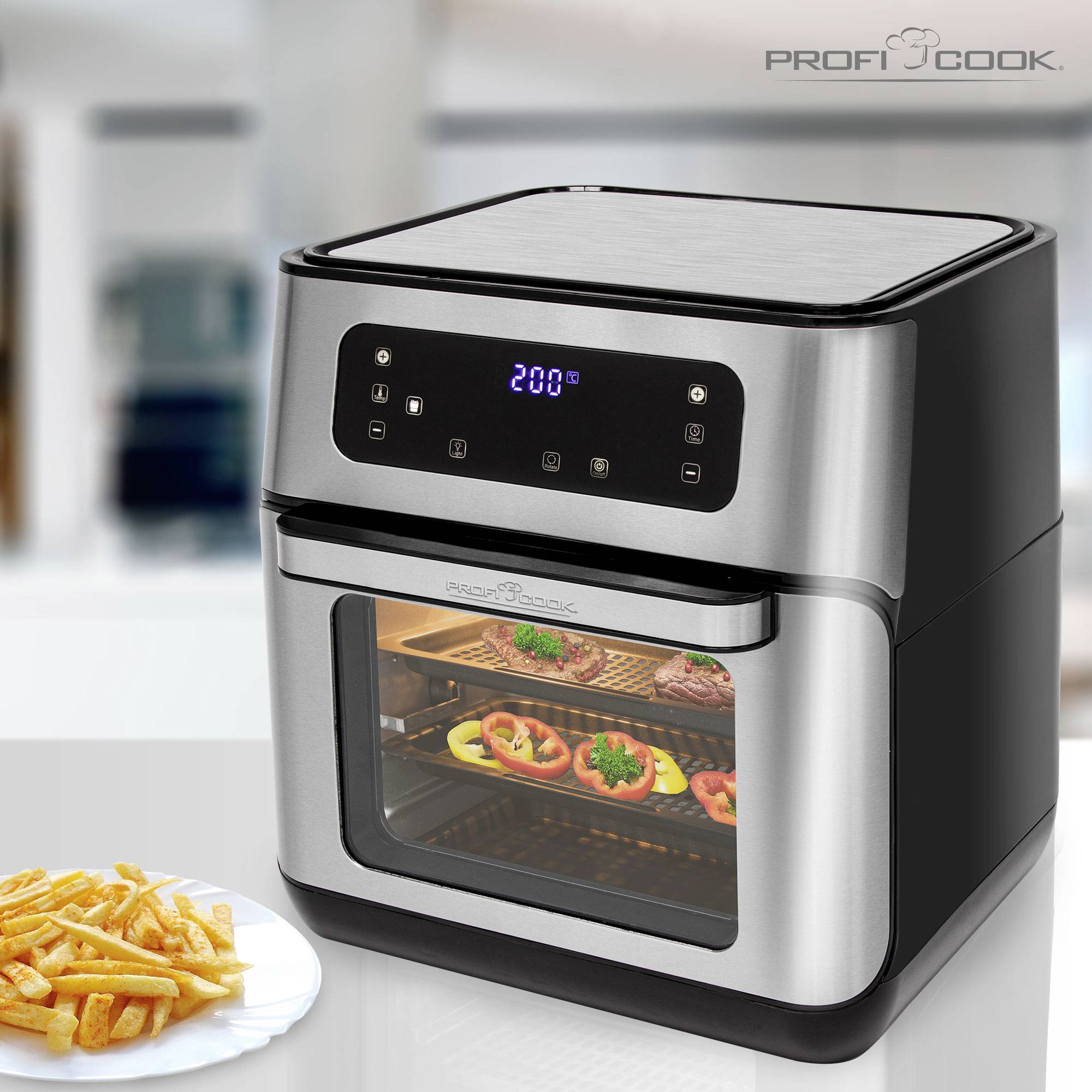 Friggitrice ad aria calda con display digitale che mostra 200 gradi Celsius. All'interno dello scomparto, verdure e carne cucinano su griglie metalliche. Patatine fritte su un piatto accanto.