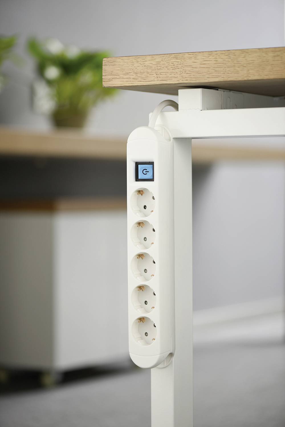 Una multipresa con cinque prese è fissata sul lato di una scrivania.