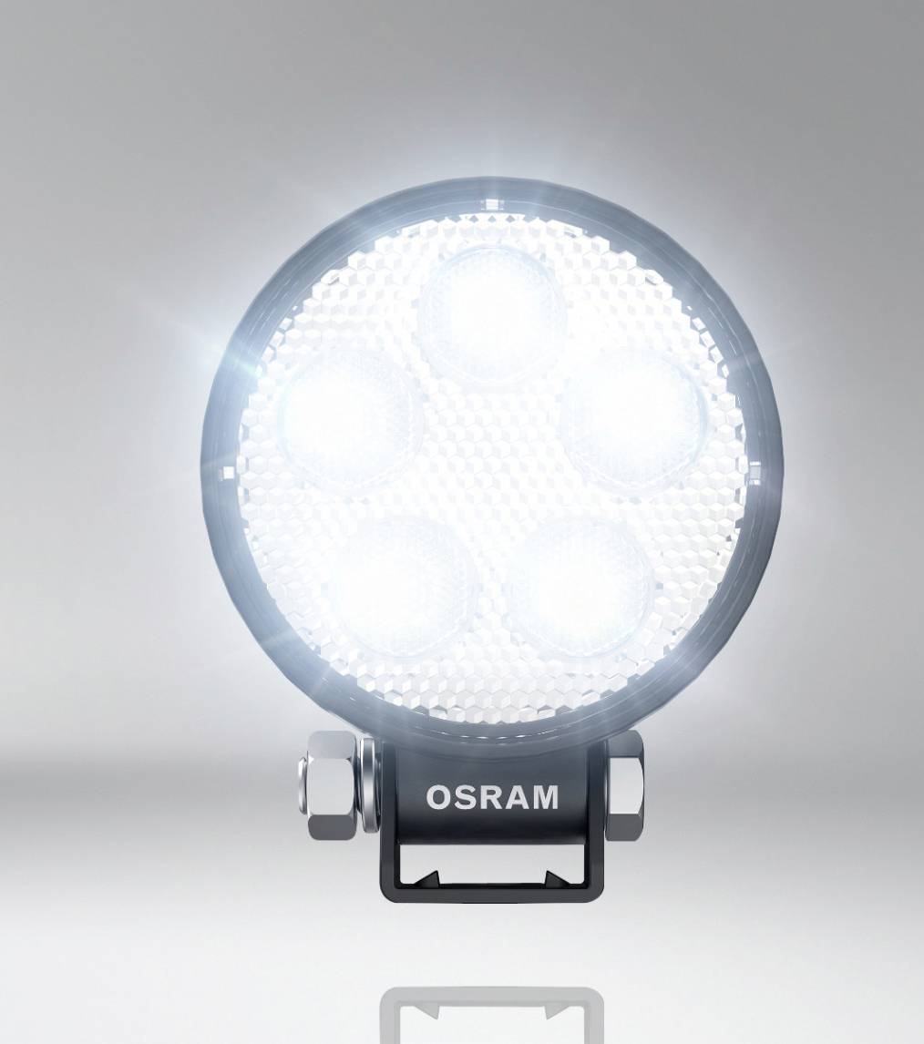 Un faro LED rotondo illumina intensamente, montato su un supporto metallico con la scritta 'OSRAM'.
