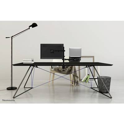 Una scrivania moderna con un monitor, un laptop, libri e una lampada da tavolo. Sullo sfondo una sedia e un cestino della carta.