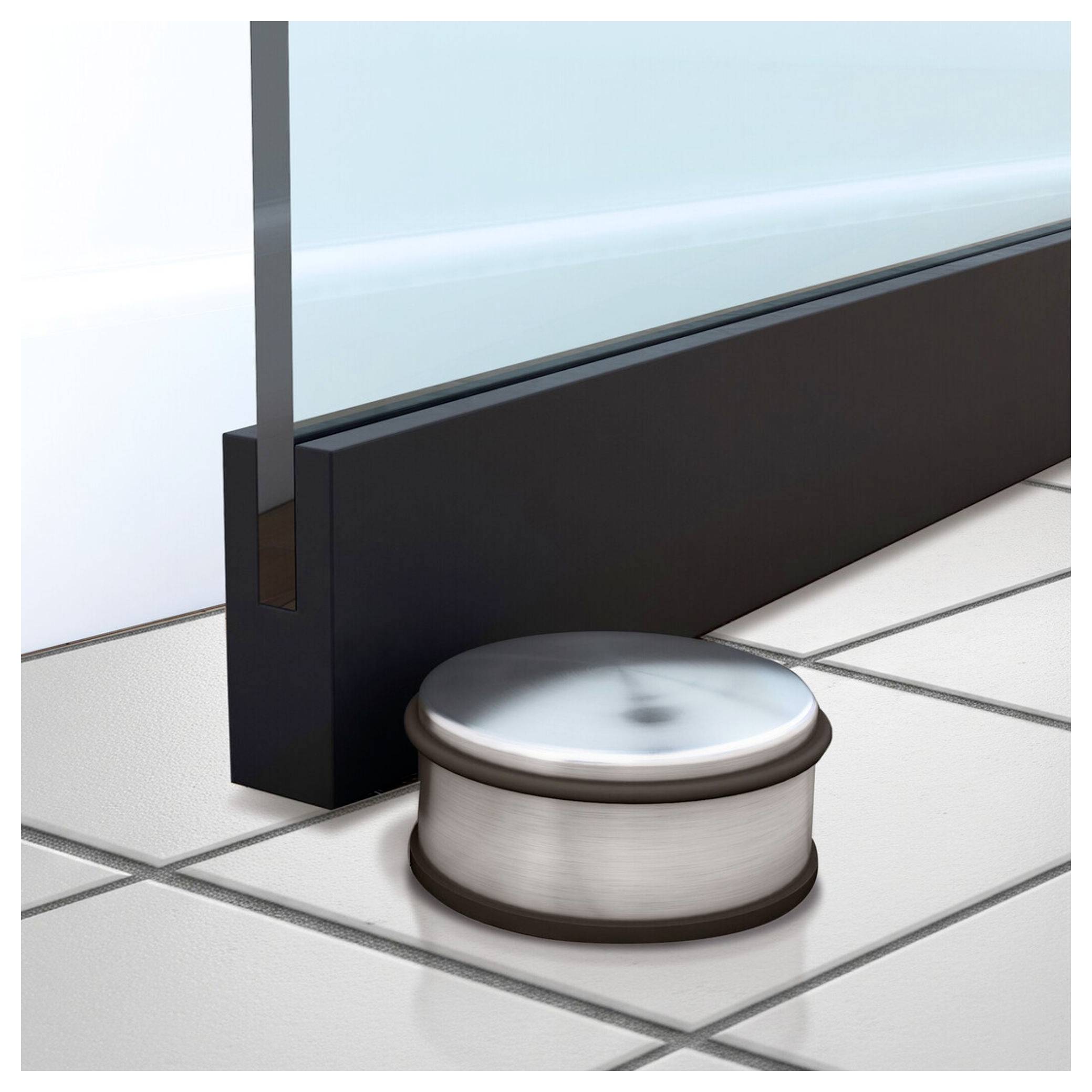 'Un fermaporta in acciaio inossidabile è posizionato su un pavimento piastrellato accanto a una porta di vetro. Impedisce alla porta di colpire il muro dietro di essa.'