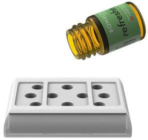Una bottiglia aperta di olio essenziale è posizionata accanto a un diffusore bianco con fori, pronto all'uso.
