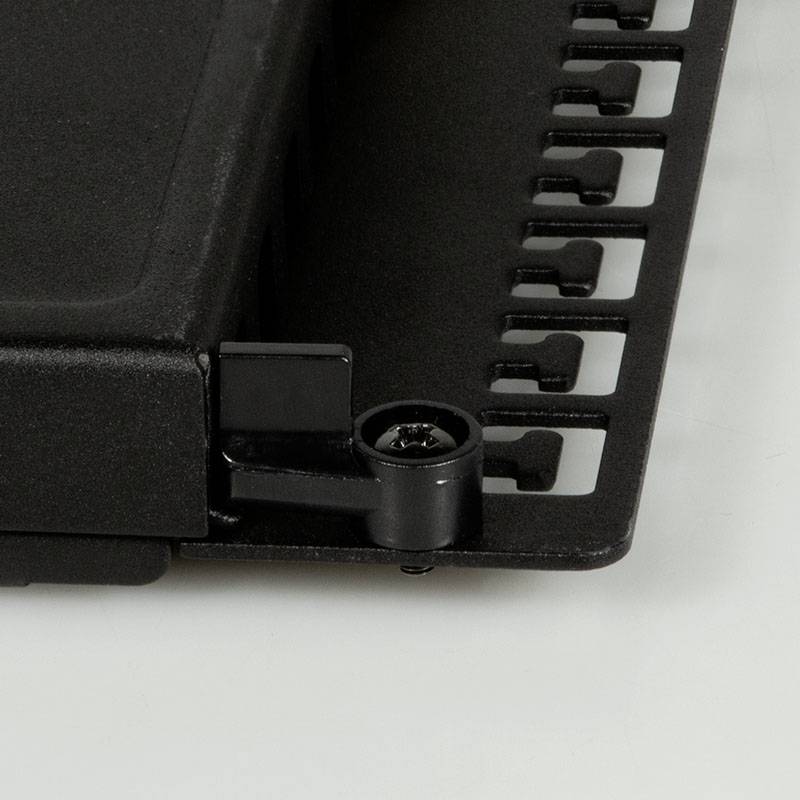 Un componente nero in plastica di forma rettangolare con bordi dentellati. Sembra essere un pezzo meccanico o tecnico.