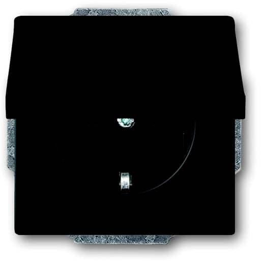 Una presa elettrica nera con coperchio di protezione chiuso, montata su una parete.