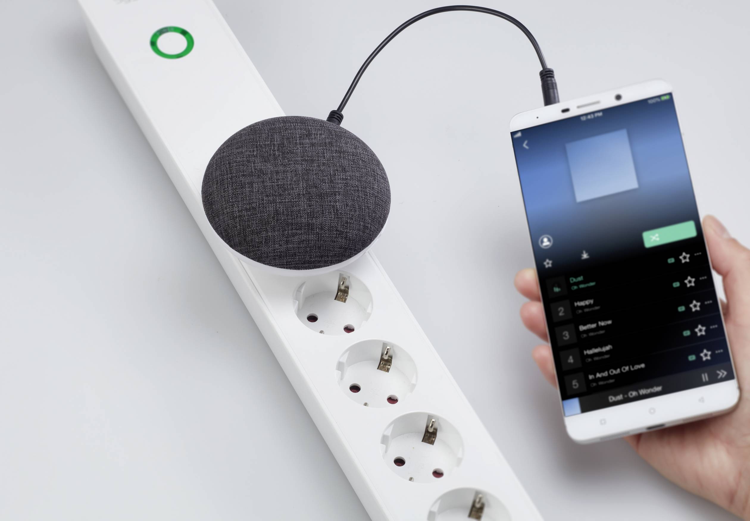 Una presa multipla intelligente collega un altoparlante e uno smartphone su cui viene riprodotta musica.