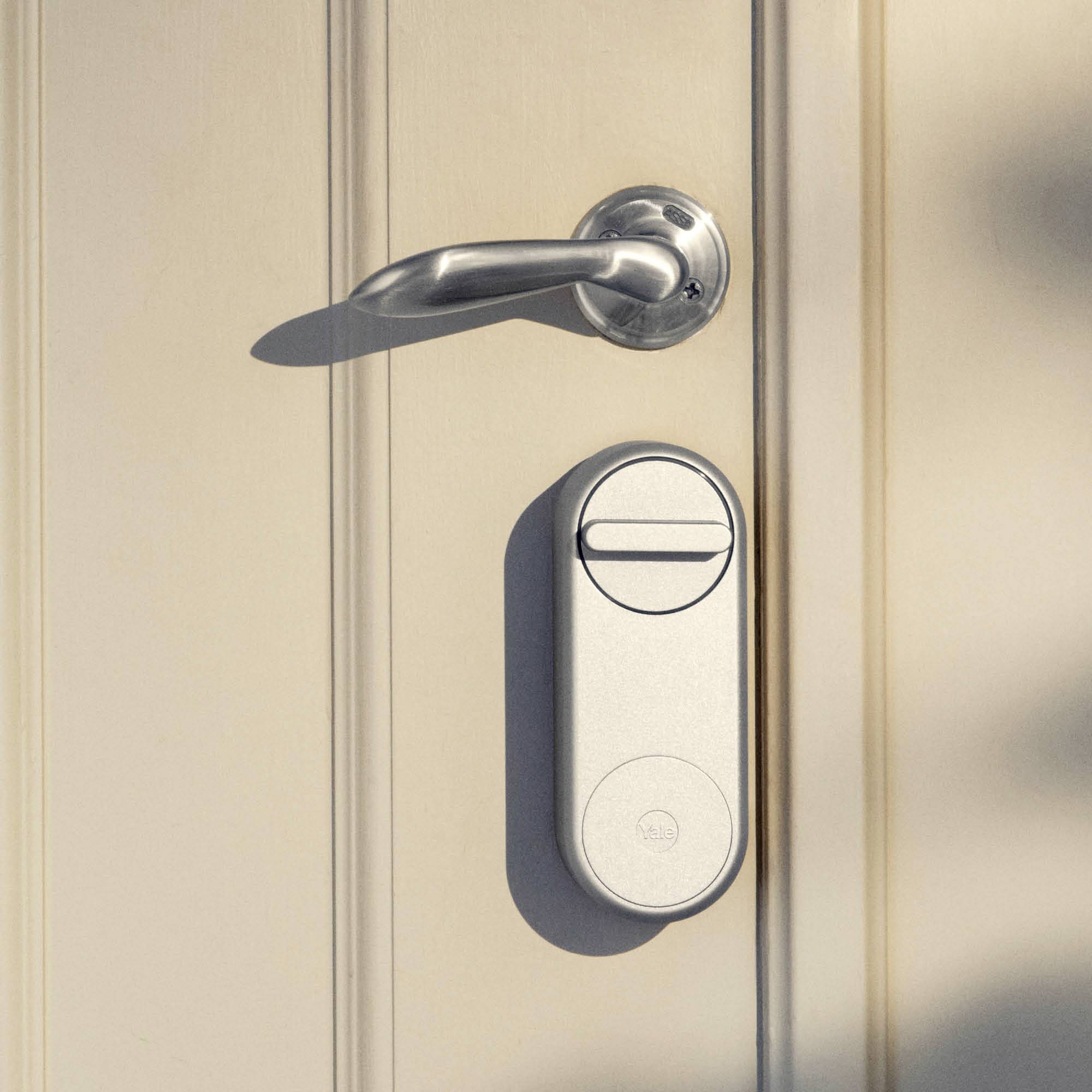 Una porta beige con una maniglia argentata minimalista e una serratura elettronica moderna sotto di essa.