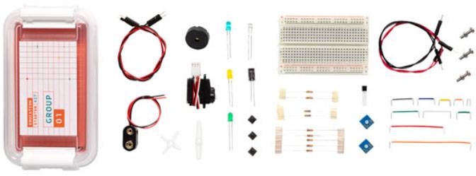 Kit elettronico con breadboard, cavi, interruttori e vari componenti elettronici su uno sfondo bianco.