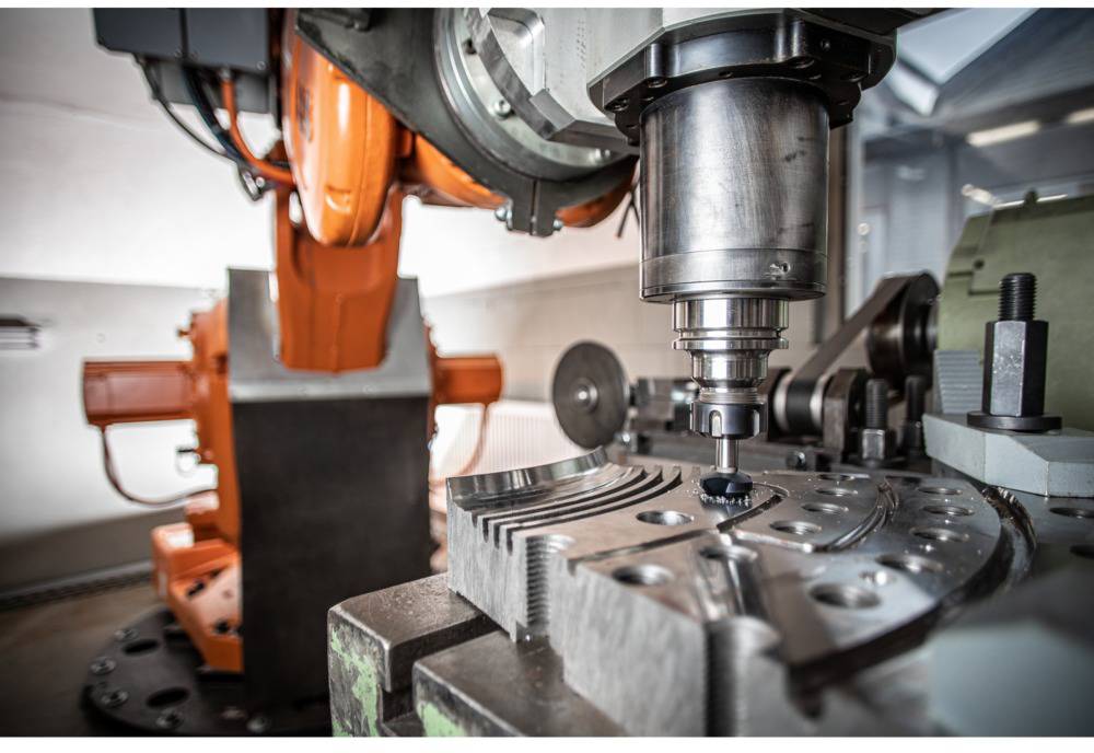 Robot industriale lavora un pezzo di precisione su una macchina CNC in una fabbrica moderna.