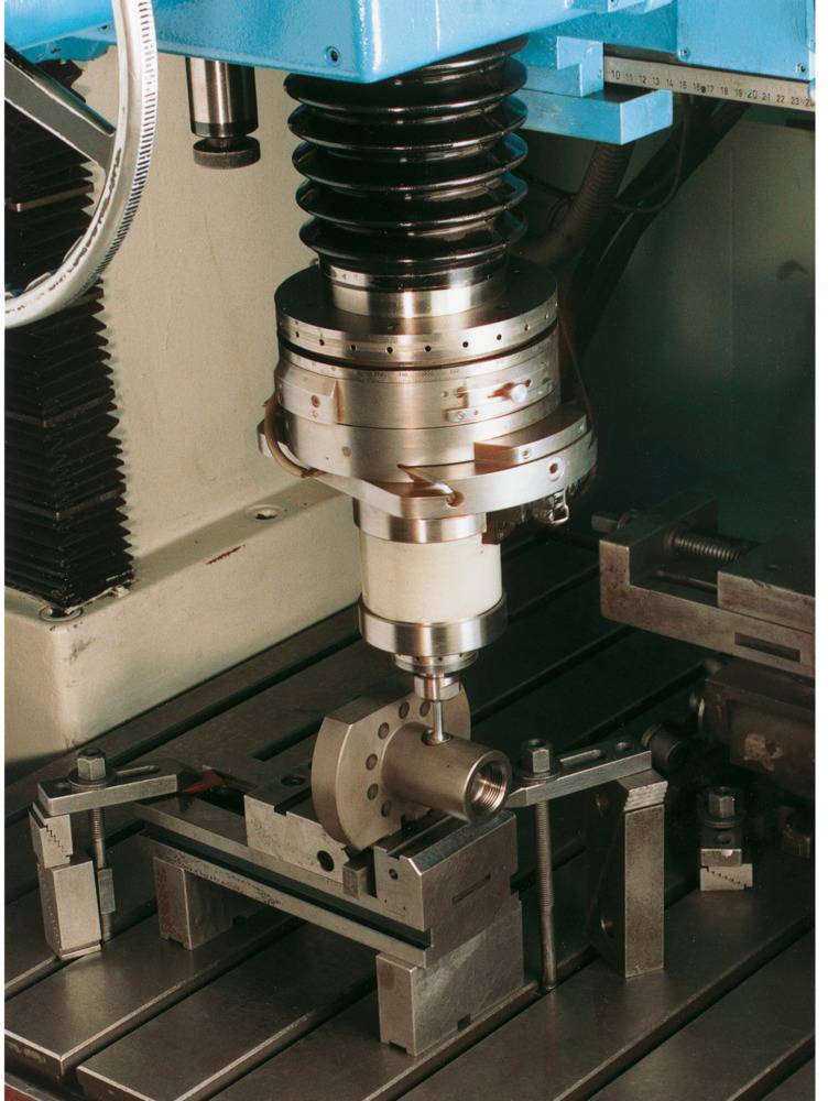 Una macchina CNC lavora un pezzo di metallo su un tavolo fresatore. La scena mostra l'allineamento preciso e la lavorazione del materiale.