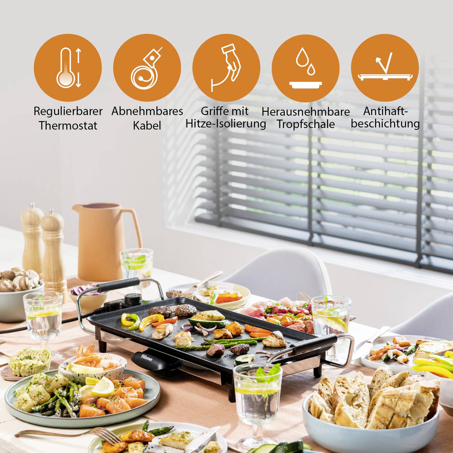 Griglia elettrica in sala da pranzo con cibo sul tavolo. Simboli in alto: 'Termostato regolabile', 'Cavo removibile', 'Manici con isolamento termico', 'Vassoio raccogli-grassi estraibile', 'Rivestimento antiaderente'.