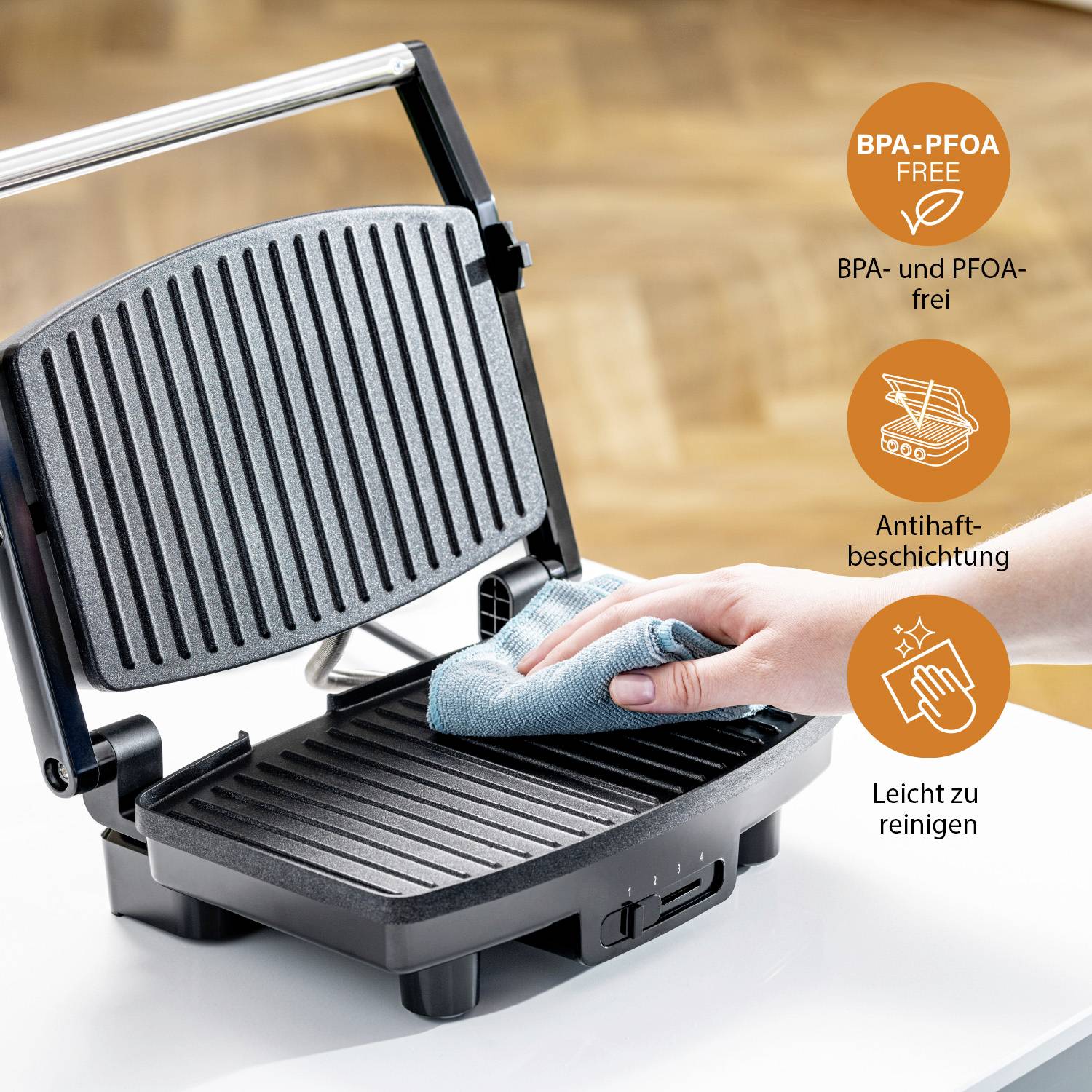 Un barbecue elettrico viene pulito con un panno. Testo: 'Privo di BPA e PFOA, rivestimento antiaderente, facile da pulire'.