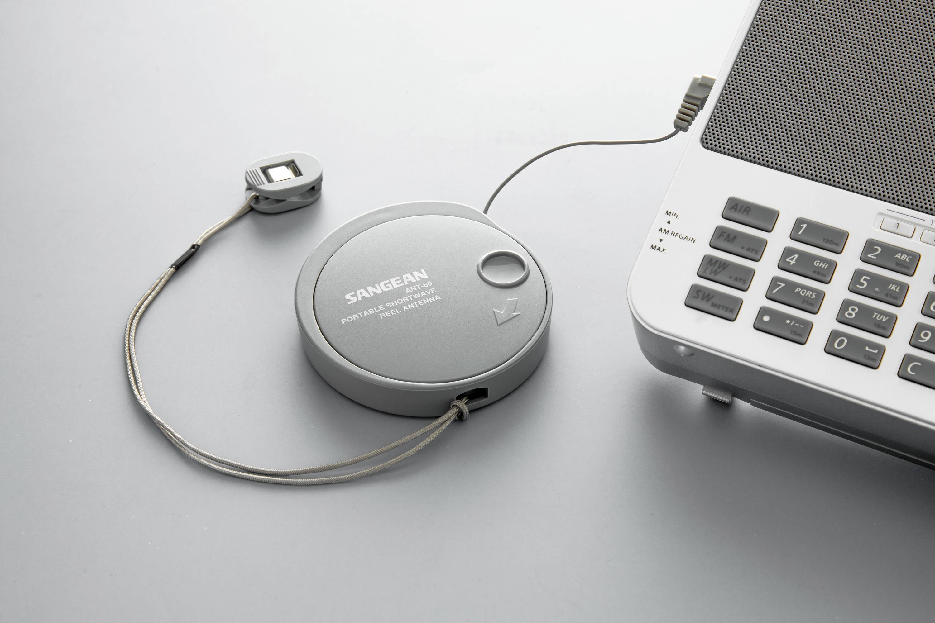 Radio portatile Sangean, collegato a un laptop, mostra un utilizzo ibrido di segnale radiofonico tradizionale e tecnologia moderna.