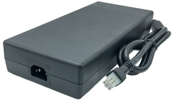 Un alimentatore nero con un connettore a tre poli e un cavo di alimentazione. Serve per l'alimentazione elettrica di dispositivi elettronici.