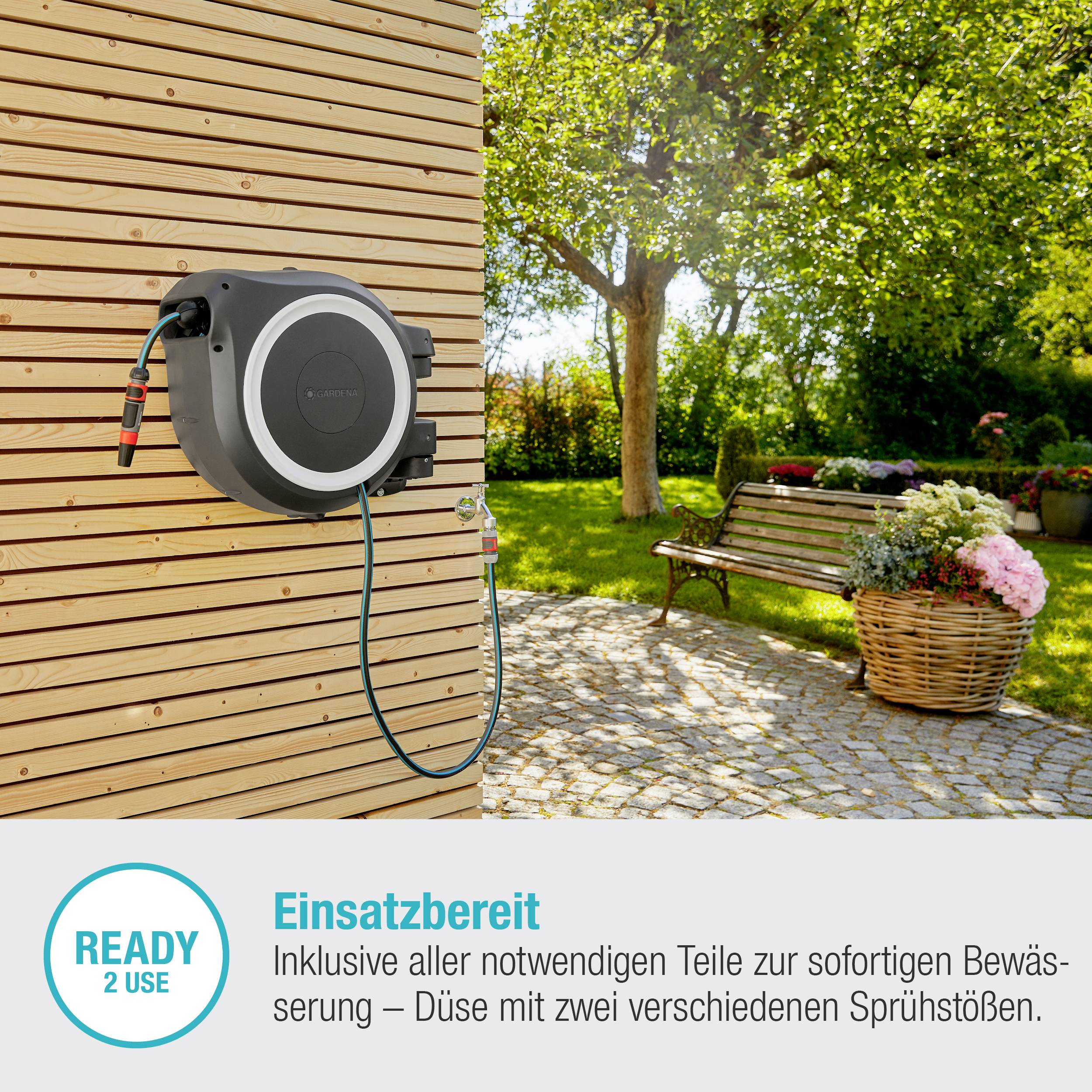 Un avvolgitubo automatico per giardino è installato su una parete di legno. Sul lato sinistro è scritto: 'Pronto all'uso - Inclusi tutti i componenti necessari per l'irrigazione immediata'. Sullo sfondo sono visibili alberi e un vaso per piante.