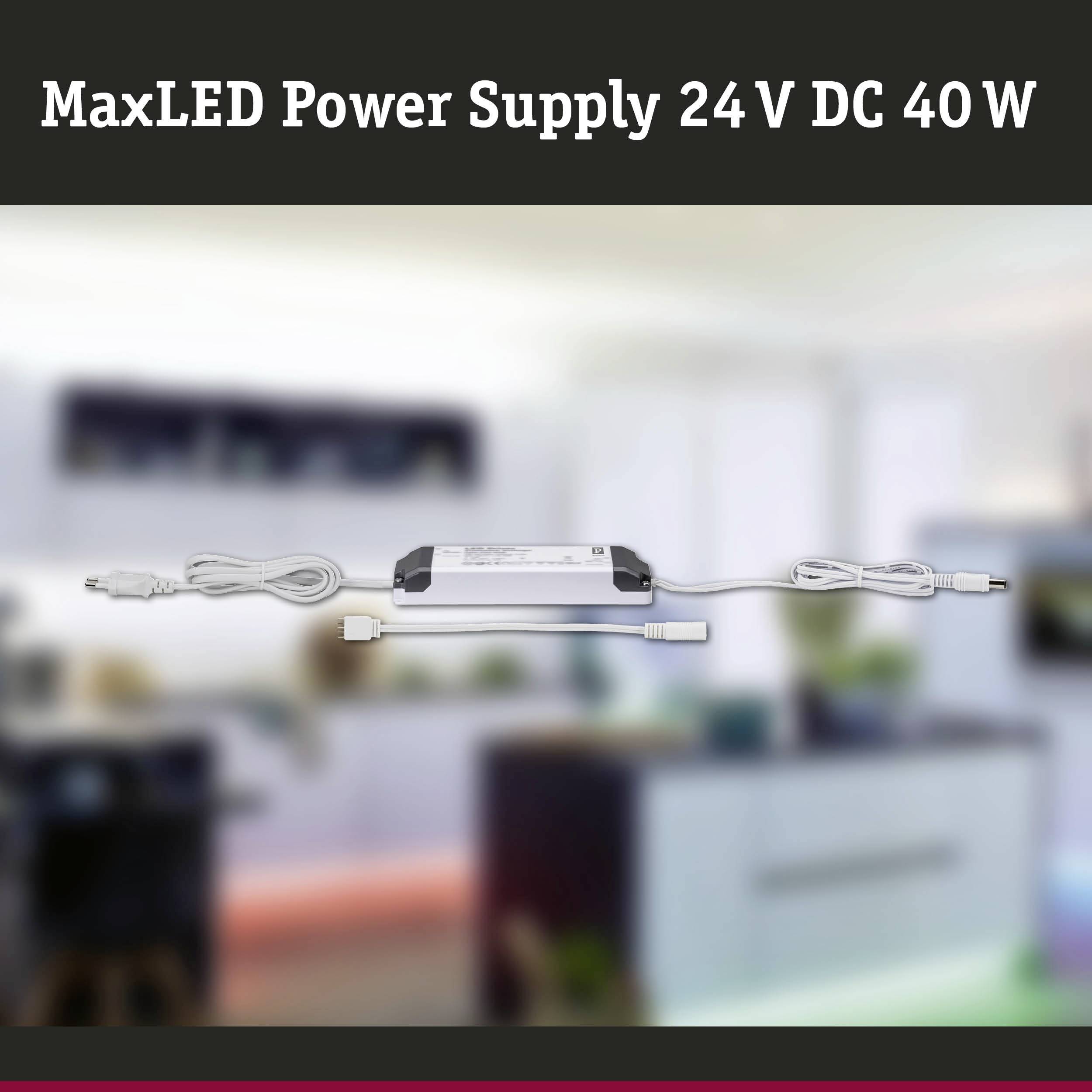 Alimentatore MaxLED 24 V DC 40 W con cavo e spina, sfondo sfocato con arredamento d'interni.