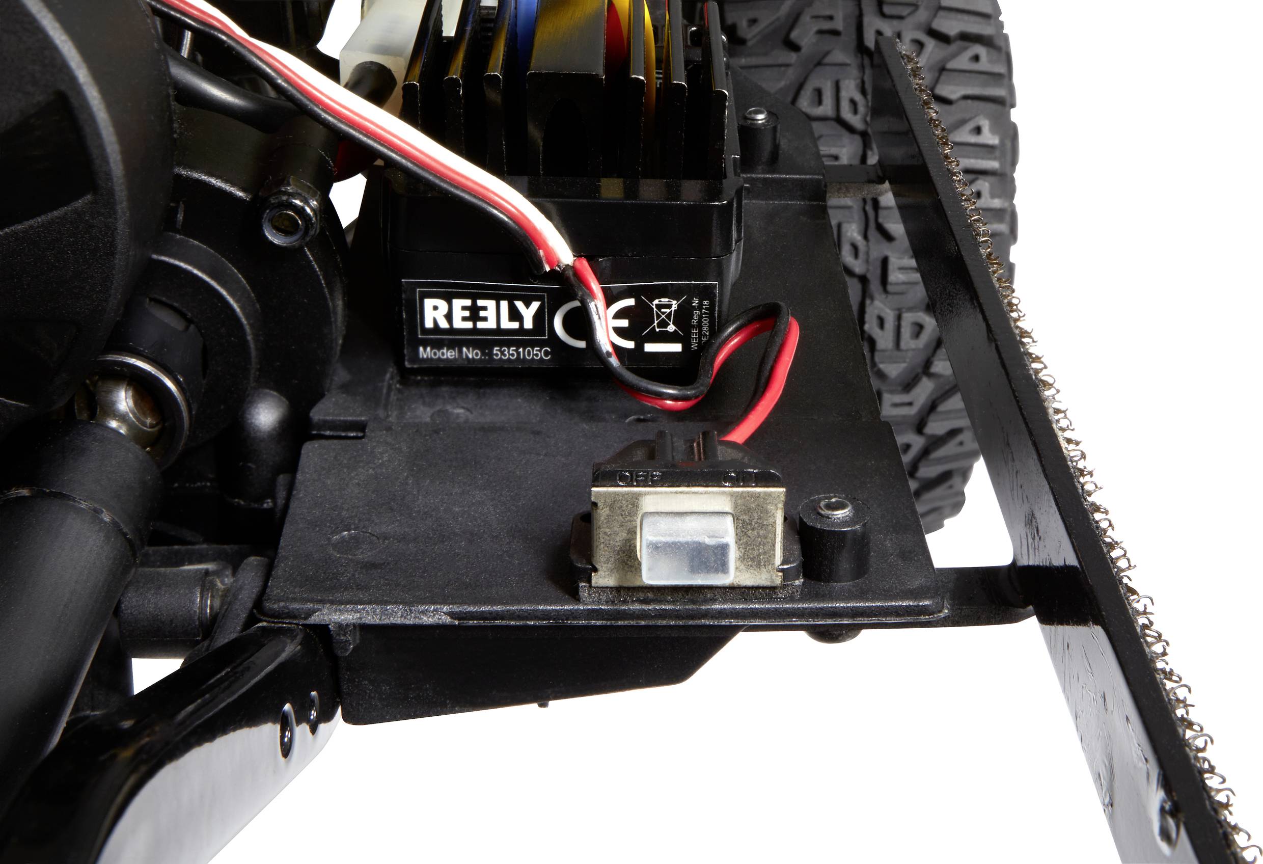 Primo piano di un veicolo modello radiocomandato: sono visibili il motore, i connettori dei cavi e una parte dei pneumatici.