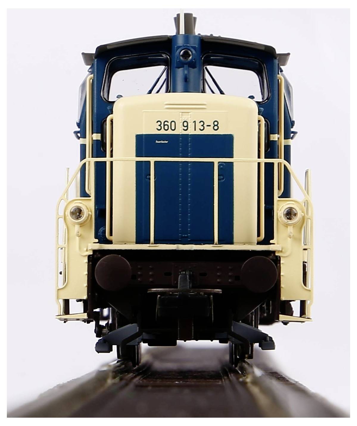 Una locomotiva modello in blu e beige vista frontalmente, che mostra il numero '360 913-8'. È posizionata su un tratto di binario.