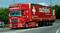Un camion rosso con la scritta 'schöni' e 'Yes, we can!' sta guidando su una strada. Lo slogan e una bandiera svizzera sono visibili.
