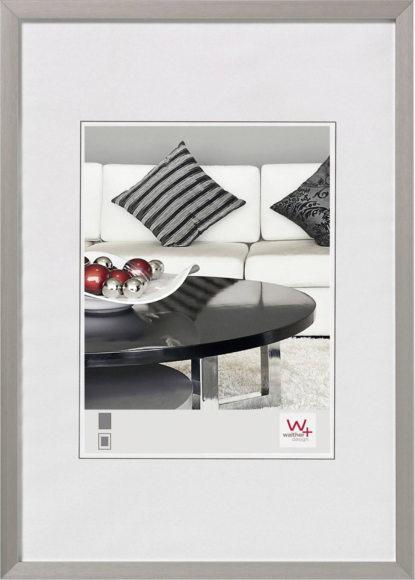 Un ambiente elegante con un divano bianco, cuscini in bianco e nero e un tavolino rotondo con sfere decorative argento e rosse.