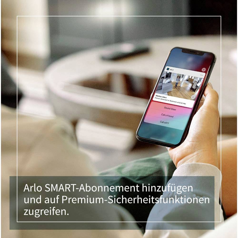 Una persona tiene uno smartphone che mostra l'app Arlo. Il testo sullo schermo incoraggia l'aggiunta di un abbonamento SMART per ulteriori funzionalità di sicurezza.