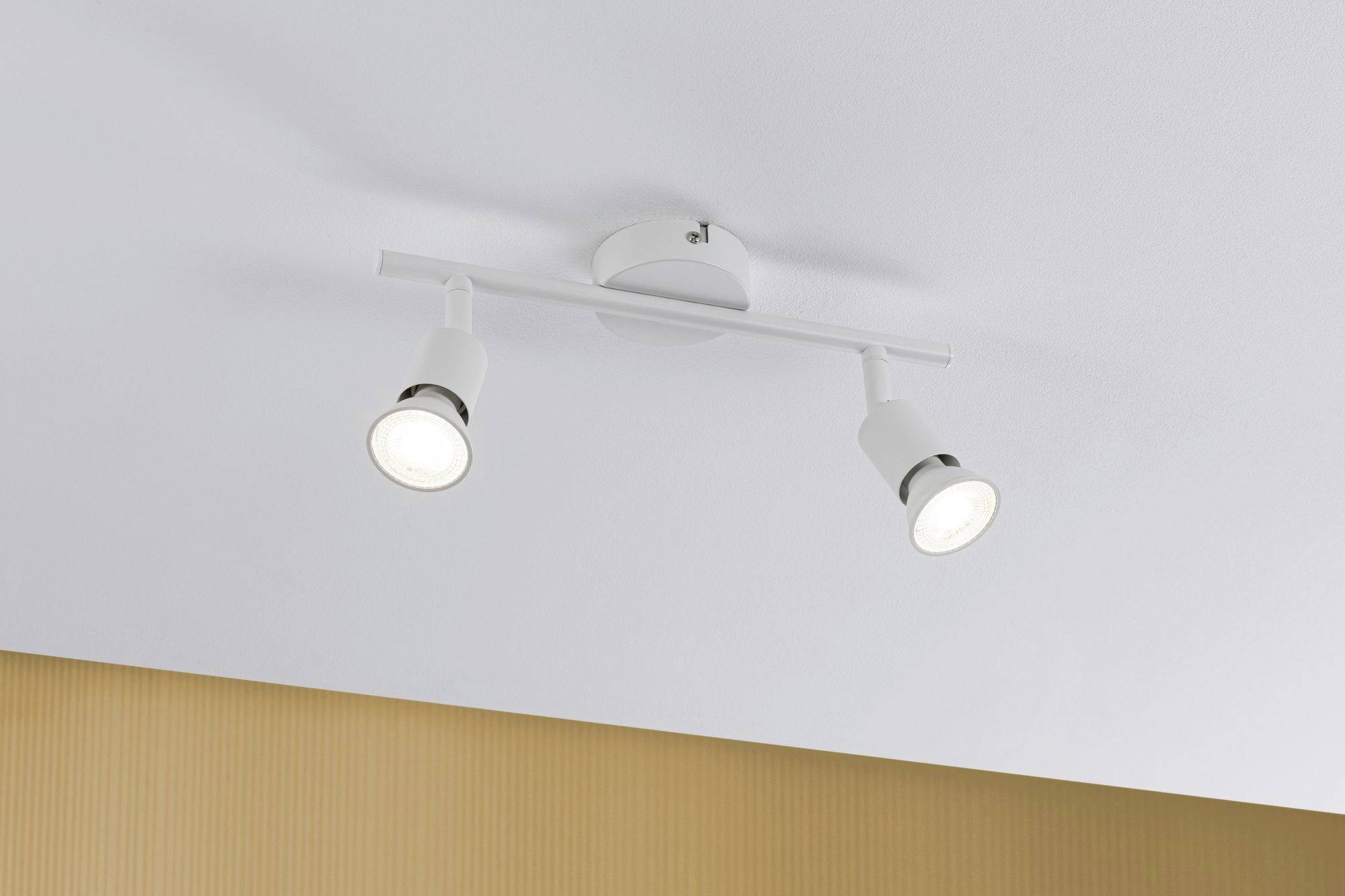Plafoniera con due faretti orientabili bianchi, fissati su un supporto bianco e installata su un soffitto bianco.