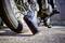 Un compressore portatile per pneumatici accanto a uno pneumatico di una moto sta gonfiando il pneumatico. Il display mostra 0,00 psi. Il sole splende sulla scena.