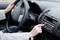 Una persona guida l'auto e aziona il pulsante della radio sul cruscotto. Primo piano sulla mano sulla radio e sul volante.