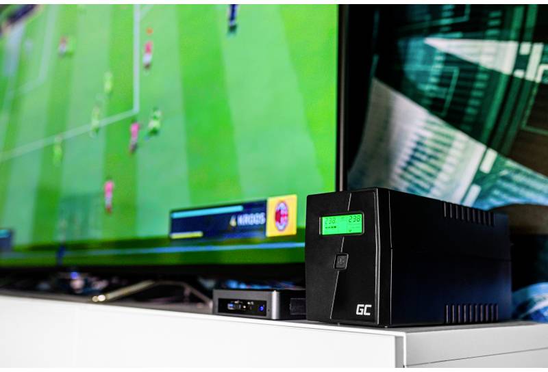 Uno schermo mostra un videogioco di calcio. Accanto ad esso c'è un UPS (uninterruptible power supply) nero con un display digitale.