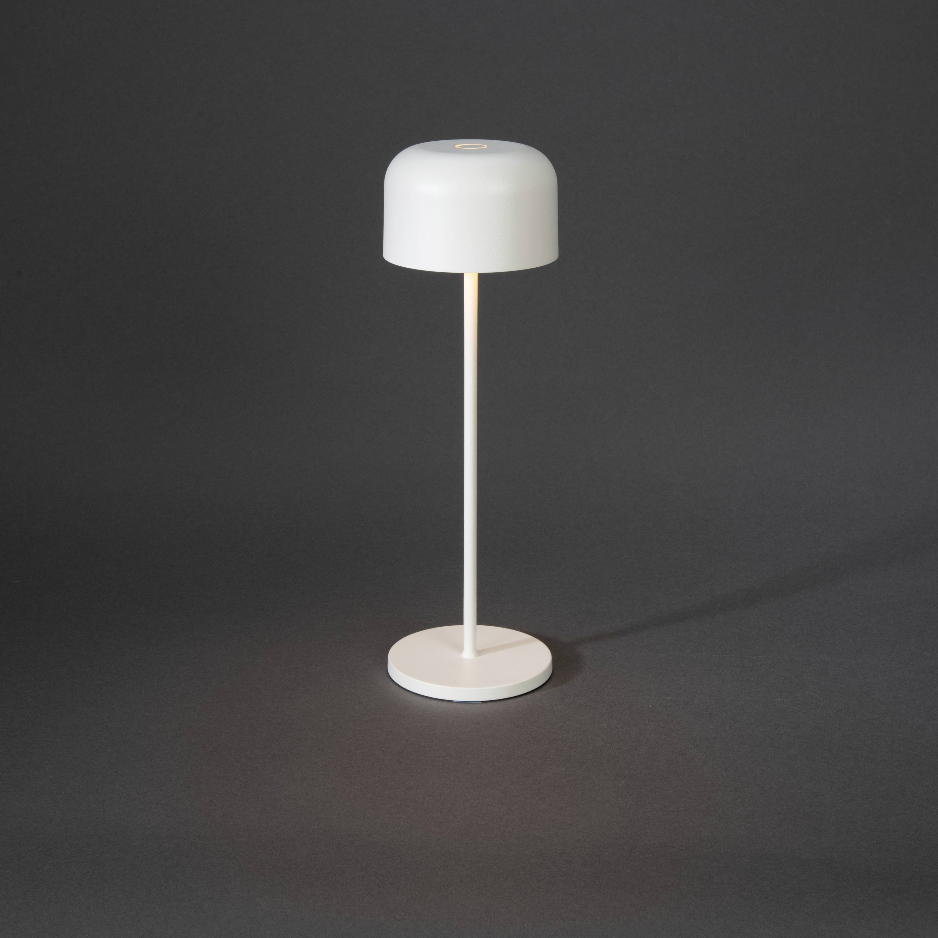 Una moderna lampada da tavolo con paralume bianco e base sottile, che emana una luce soffusa diretta verso il basso.