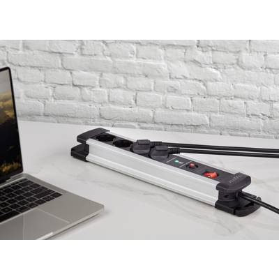 Multipresa con più prese e interruttori integrati su un tavolo. Un laptop è posizionato accanto ad essa.