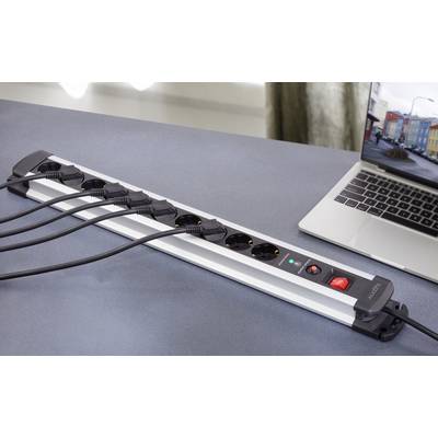 Presa multipla con diversi cavi inseriti accanto a un laptop su un tavolo. La presa è dotata di un interruttore con spia di controllo.