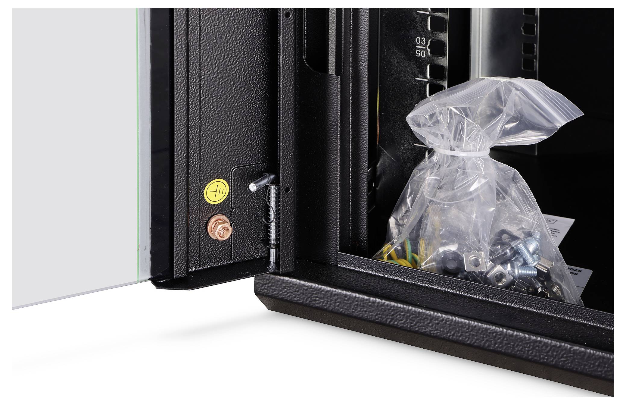 Una porta di un mobile aperto che rivela un sacchetto di plastica contenente viti e ferramenta, probabilmente per installazione o assemblaggio.