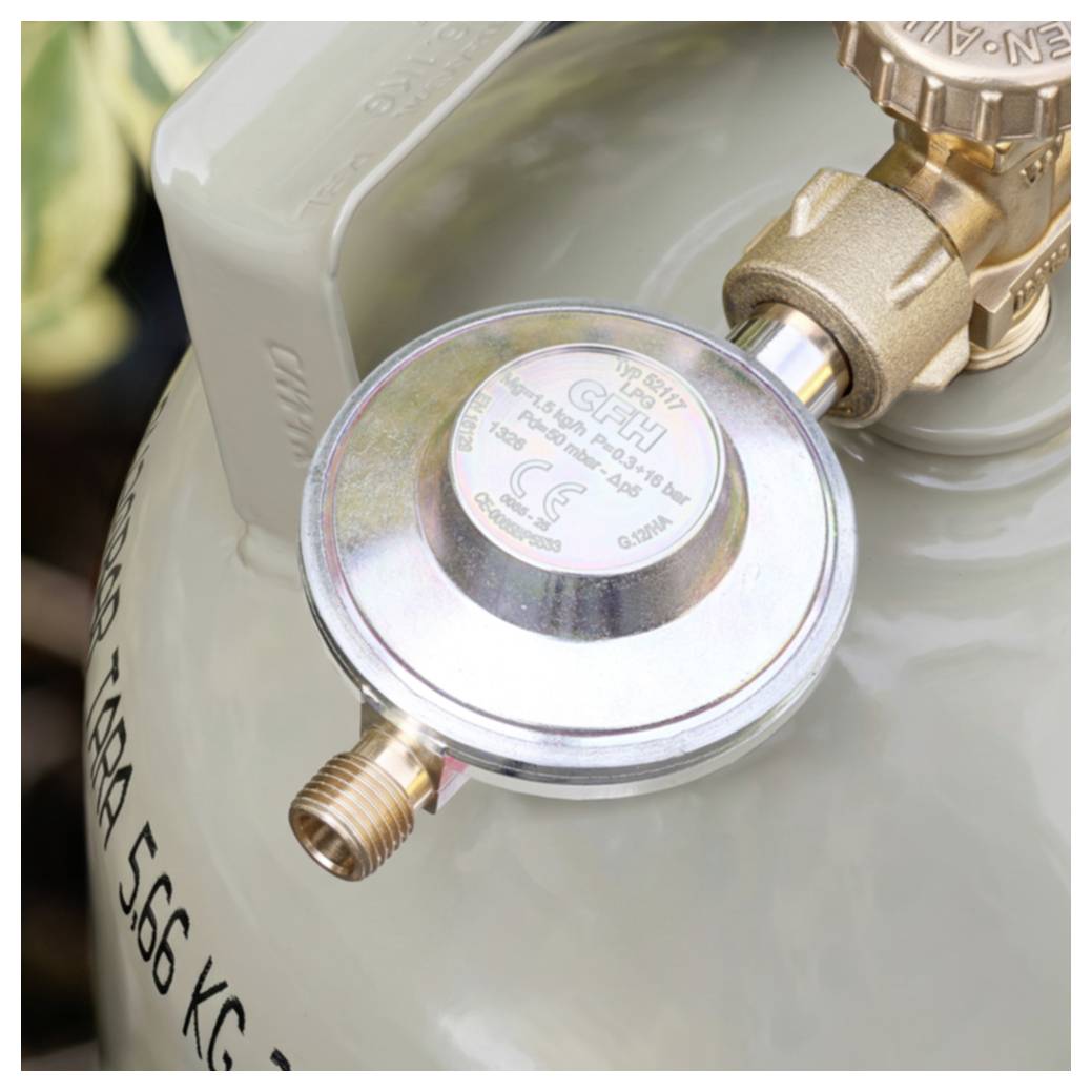 Primo piano di un regolatore di pressione per bombola di gas collegato a una valvola, con il corpo del serbatoio e il raccordo visibili.