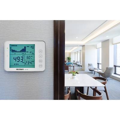Termostato digitale da parete mostra l'umidità al 49,3% e la temperatura a 23,4°C in un soggiorno moderno.