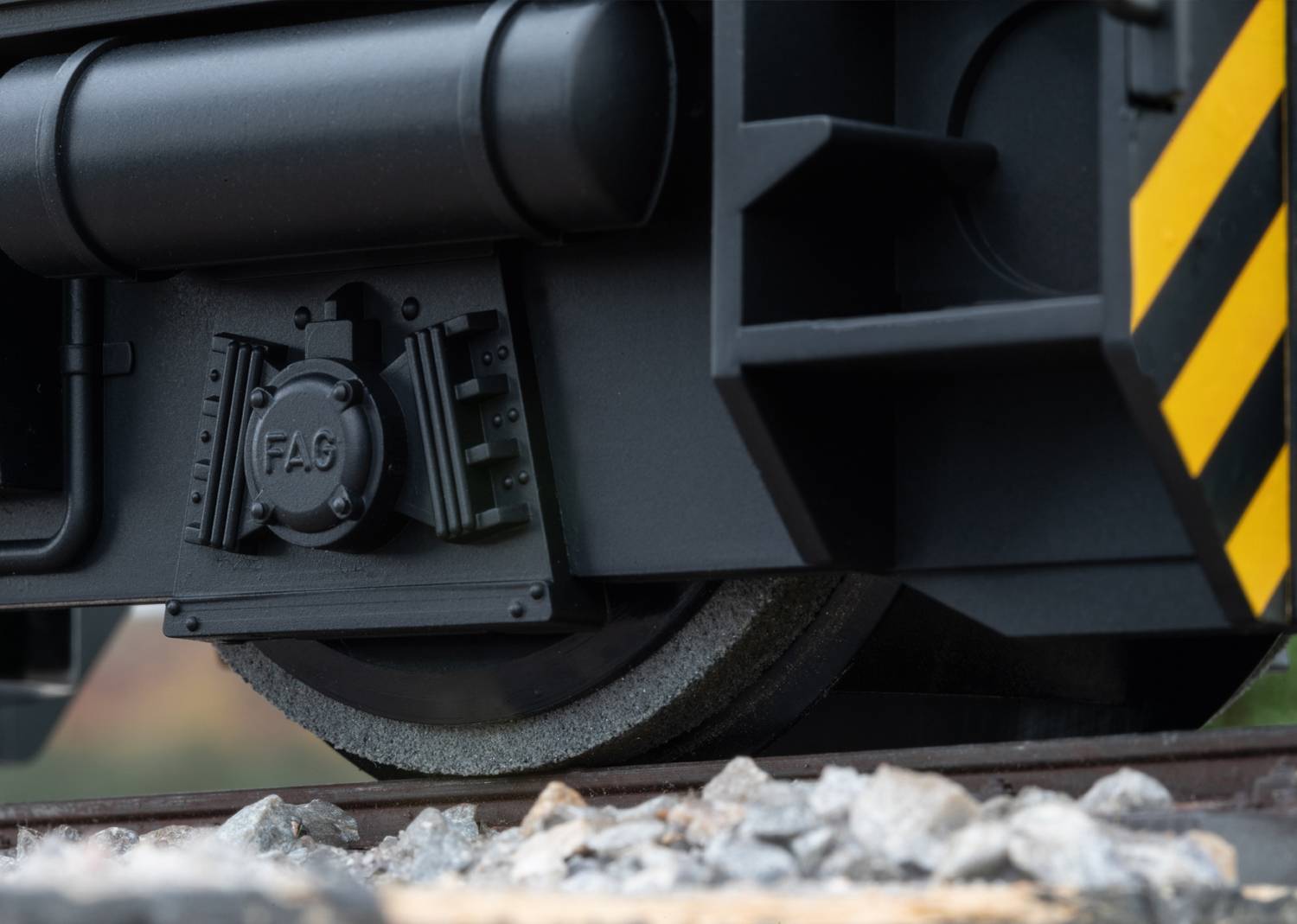 Primo piano di un treno sui binari. Dettagli nitidi delle ruote e dei binari visibili, con marcature in nero e giallo.