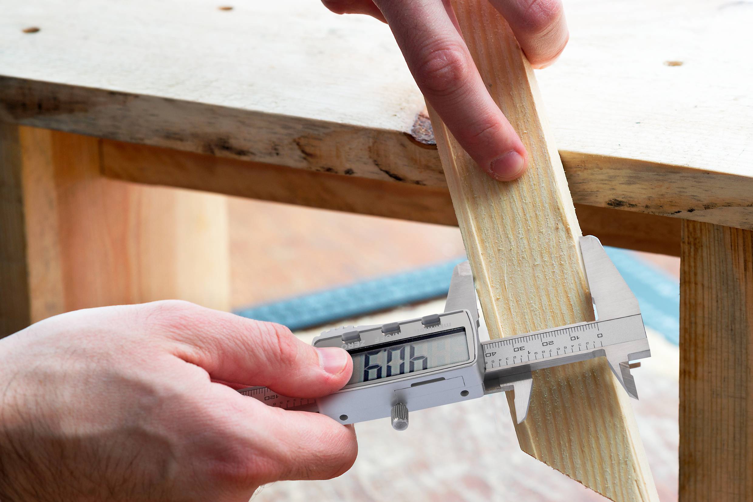 Una persona misura una tavola di legno con un calibro digitale. La scala di misurazione mostra dimensioni precise per un adattamento accurato.