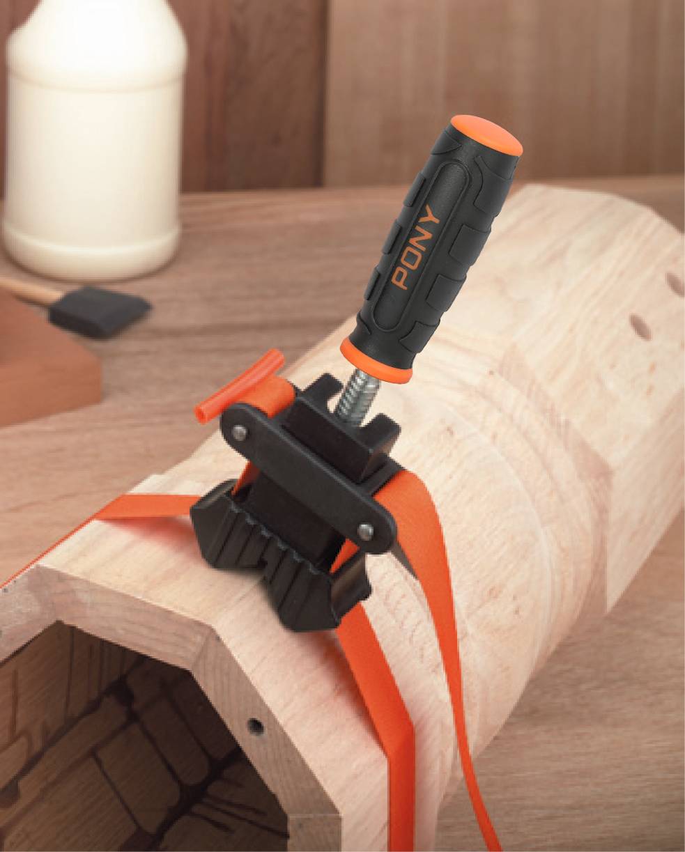 Un tubo è fissato con una pinza arancione su un banco da lavoro per facilitare le operazioni. Lo sfondo è sfocato.