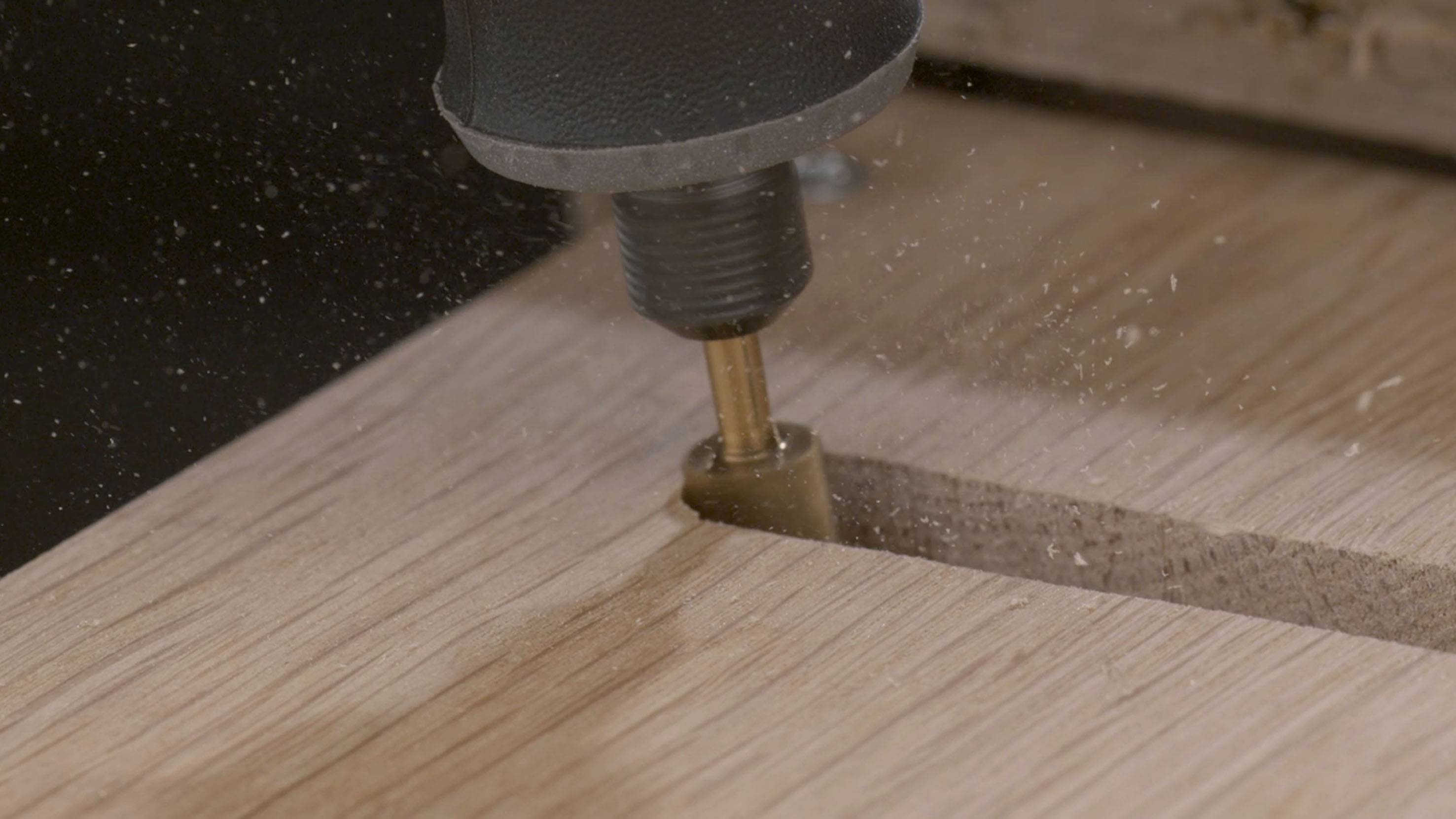 Una fresa lavora una superficie di legno, producendo trucioli di legno.