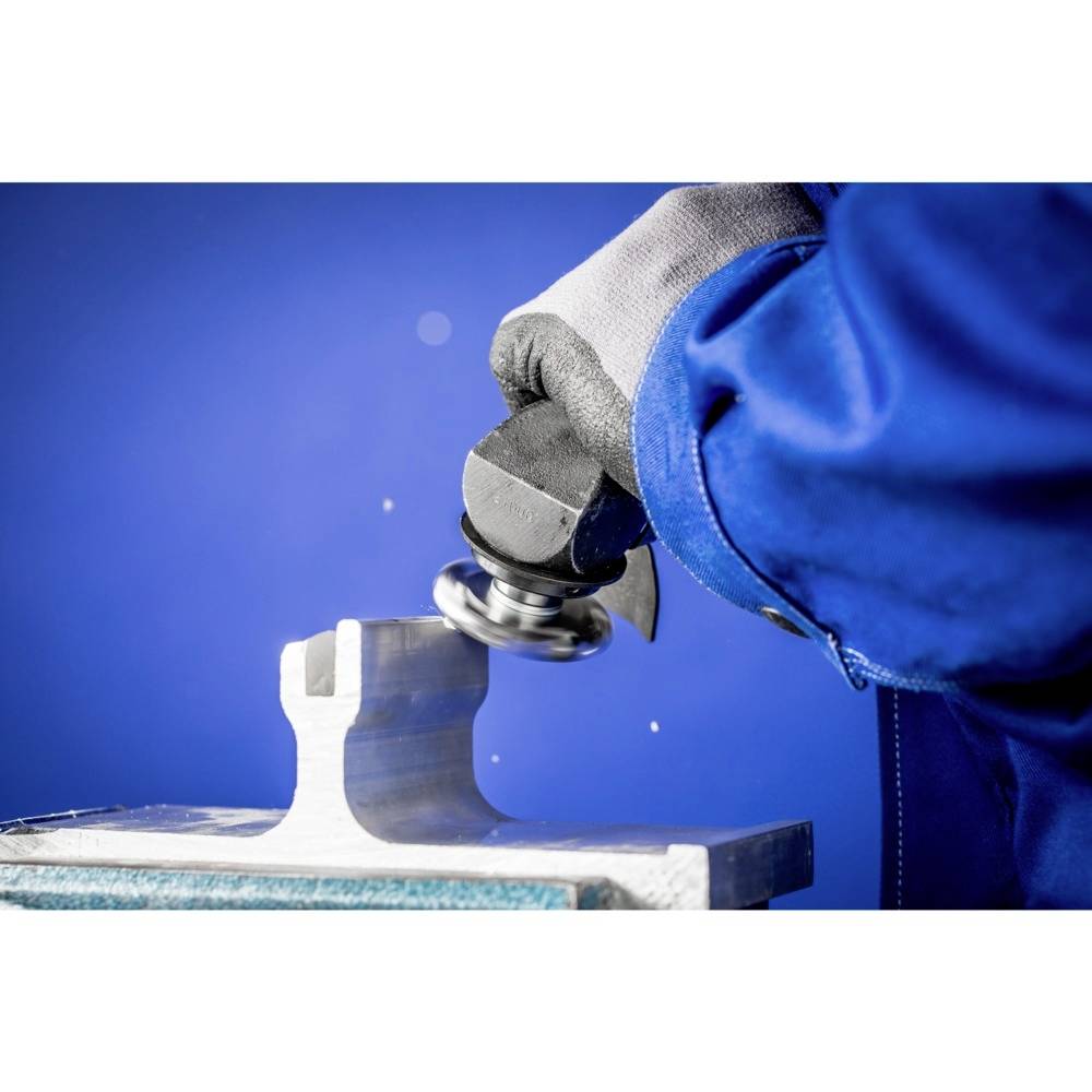 Una persona lavora con un utensile per lucidare, indossando un abbigliamento protettivo blu, su un pezzo metallico sullo sfondo di un colore blu.